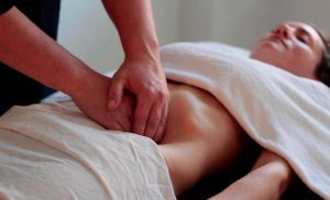 erapeuta realizando técnica de osteopatía visceral en el abdomen para tratar dolor lumbar y desequilibrios musculoesqueléticos